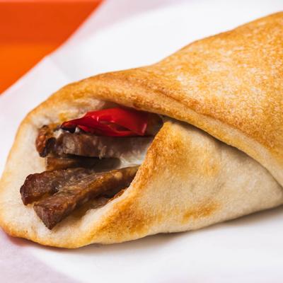 A steak and cheese wrap with a red chili pepper on top.