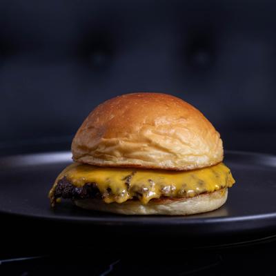 A plain cheeseburger on a black plate.