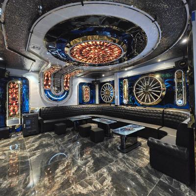Luxurious karaoke room with curved black leather sofa and coffee tables.