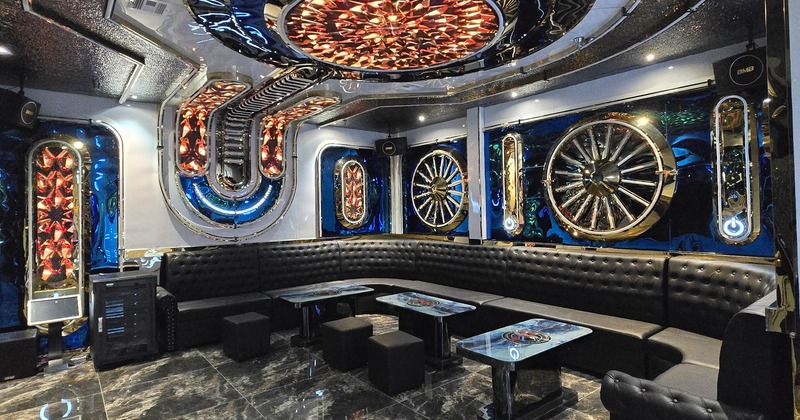 Luxurious karaoke room with curved black leather sofa and coffee tables