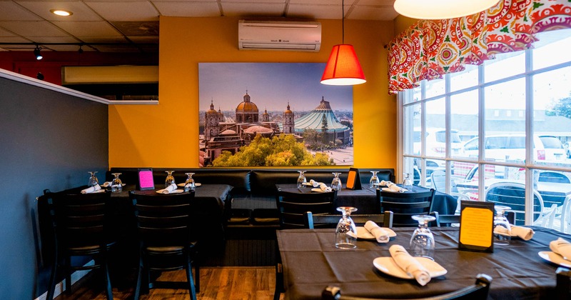 Interior, banquette seating  and set tables , wall decorated with a large picture