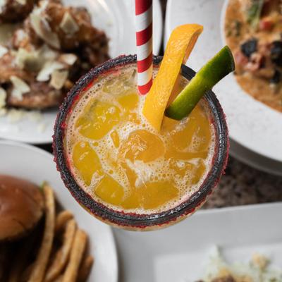 Margarita cocktail surrounded by food plates, top view.