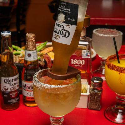 Coronarita in a salt-rimmed glass, garnished with an upside-down beer bottle.