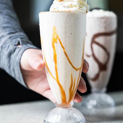 A hand grabbing a milkshake.