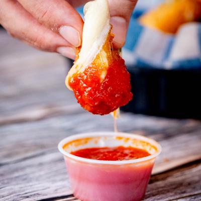 Mozzarella Stick dipped in tomato sauce, close up.