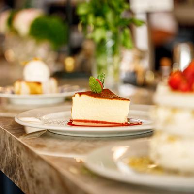A slice of cheesecake with raspberry sauce and a mint leaf garnish.