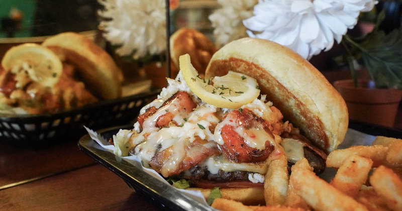 A burger with shrimp, bacon, cheese, and fries