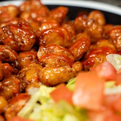 Glazed boneless chicken bites with chopped tomato lettuce salad.