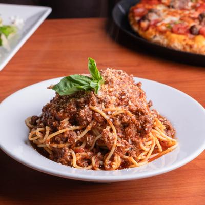 Spaghetti pasta meal featuring a hearty meat sauce and fresh basil garnish.
