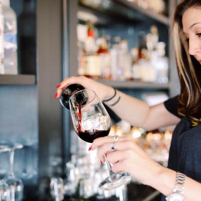 Bartender pouring red wine into a glass.