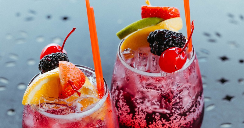 Two berry cocktails garnished with fresh fruit