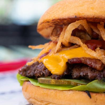 Close-up of a gourmet cheeseburger with crispy onion straws and pickles.