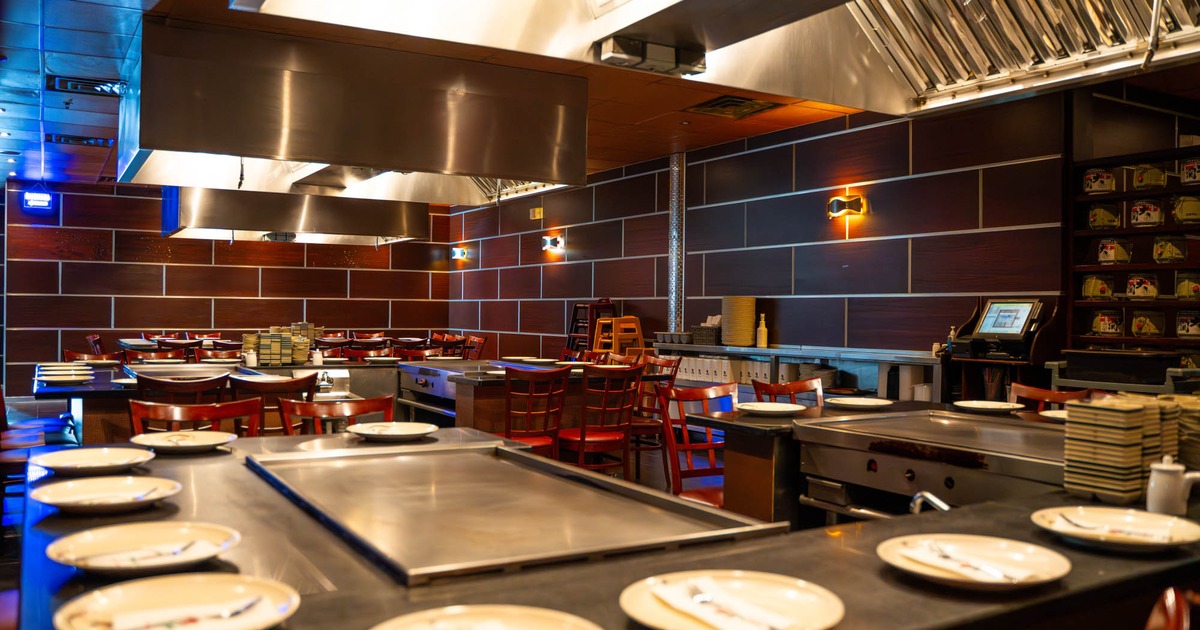 Interior, hibachi grill tables for ten people, red wooden stools, large format tiles on the wall