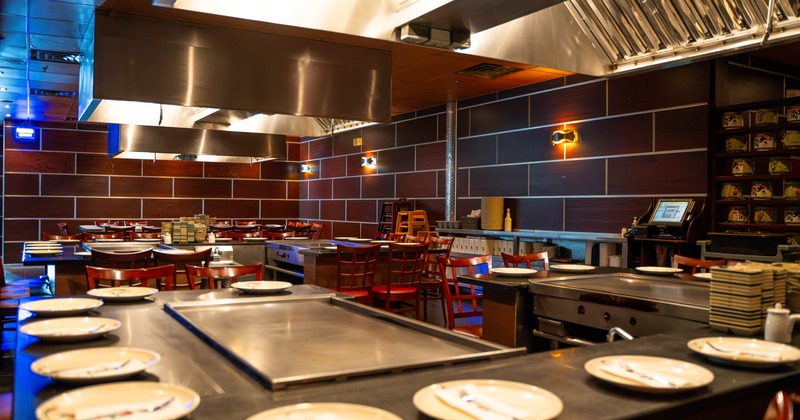 Interior, hibachi grill tables for ten people, red wooden stools, large format tiles on the wall