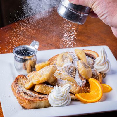 Powdered sugar being sprinkled on Banana French Toast.