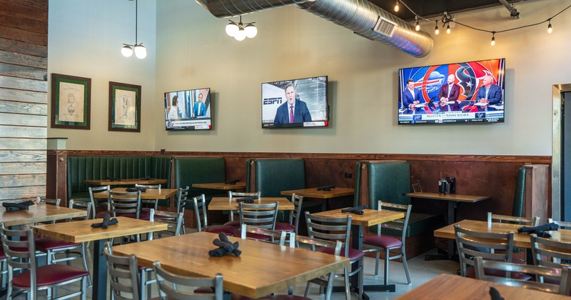 Modern interior with tables, booths and multiple wall-mounted televisions.