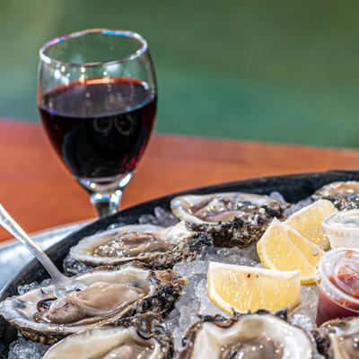 Clams on ice, two dips, lemon and glass of red wine