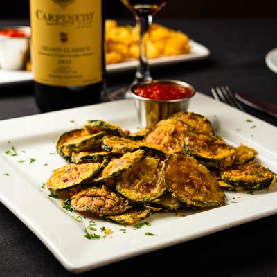 Zucchini chips served with a cup of marinara sauce.
