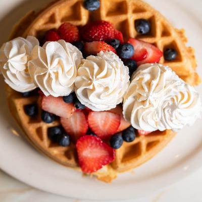 Waffle topped with fresh berries and whipped cream.