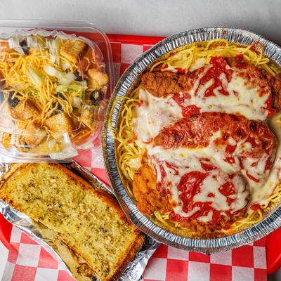 Chicken Parmesan, Caesar Salad, and garlic bread on a tray.