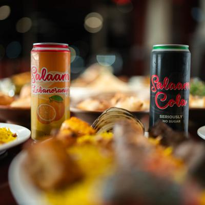 Two soda cans on a table with food.