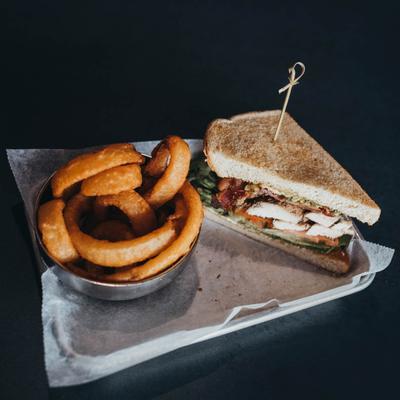 Chicken Avocado Club Sandwich, and a side of onion rings.