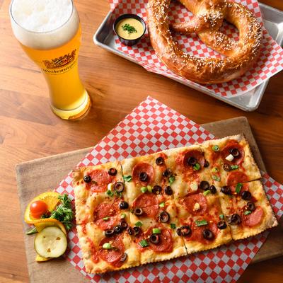Flatbread pizza, pretzel, and a glass of beer.