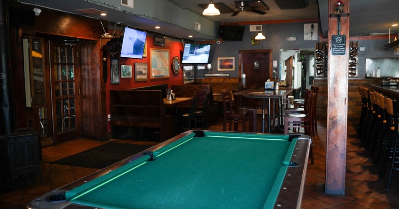 Interior, pool table in front, seating booths and bar stools with tables in the back