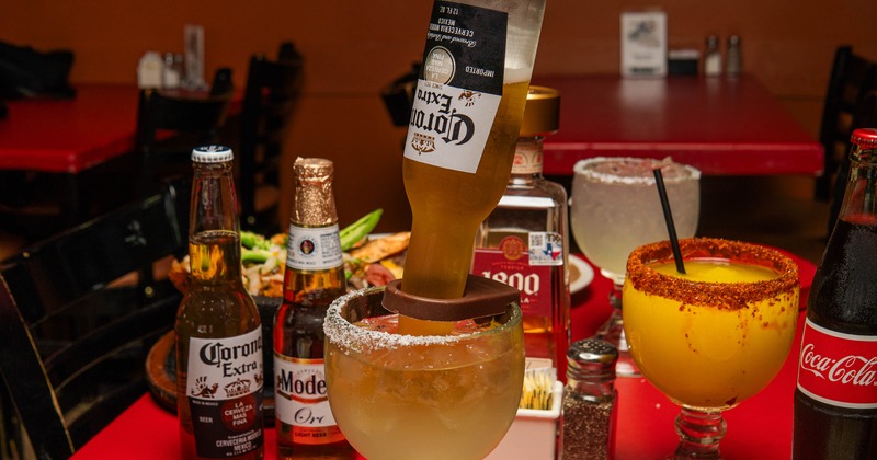 Coronarita topped with an upside-down bottle, surrounded by beer bottles and margaritas