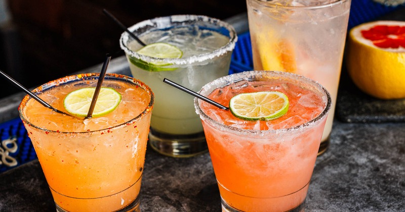 Assorted cocktail drinks sit on a bar counter