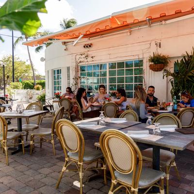 Outdoor restaurant patio with wicker chairs and tables, Group of people dining.