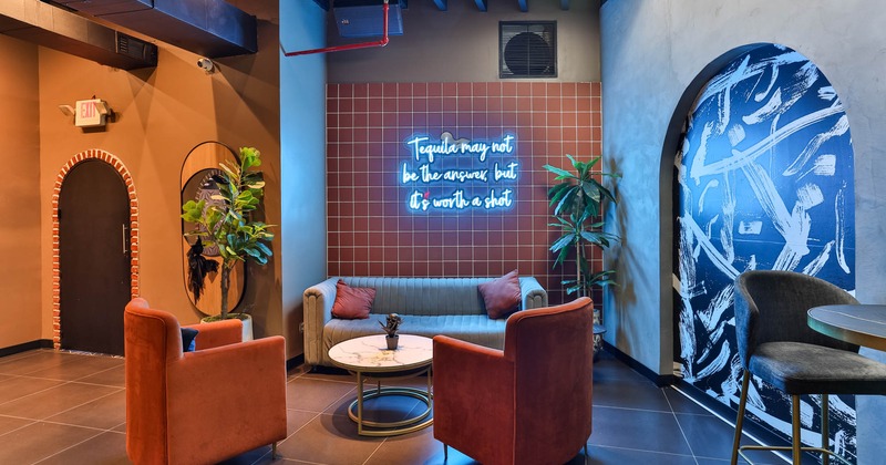 Interior, seating area lit by a neon light message on a wall