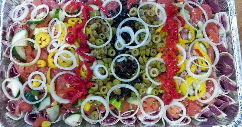 A large catering tray with antipasto salad