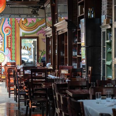 Restaurant interior with wooden chairs and tables set for dining.