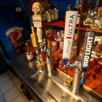 Stainless steel bar counter featuring multiple draft beer taps with branded handles.