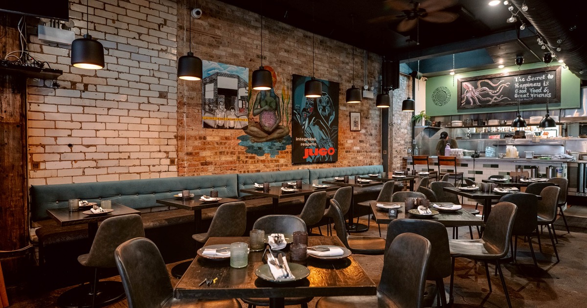Interior of a modern restaurant with exposed brick walls, and a visible kitchen