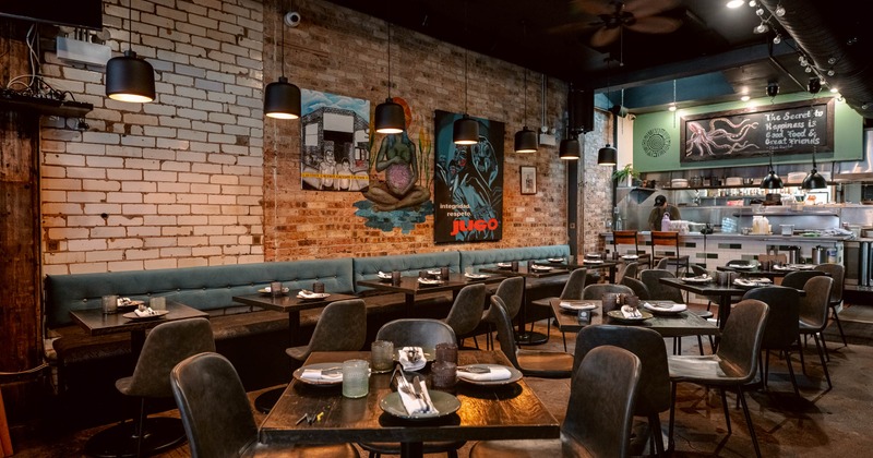 Interior of a modern restaurant with exposed brick walls, and a visible kitchen