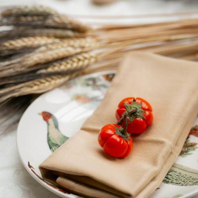 Table decorated with wheat stalks, a colorful plate with a linen napkin and tiny tomatoes.