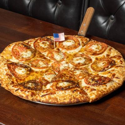 Baked pizza with tomatoes and cheese, decorated with a small American flag.