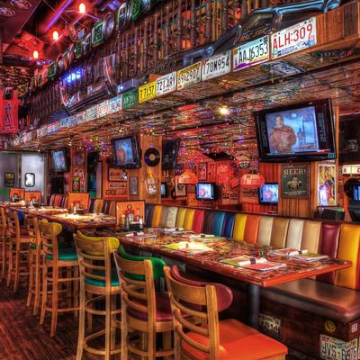 Cozy bar with colorful seats, vintage decor, and dim lighting, wall decorated with license plates