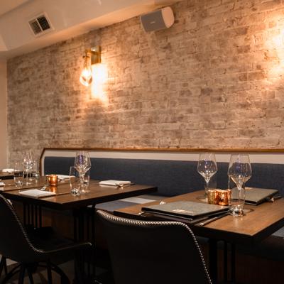Banquette by a rustic brick wall, with set tables and chairs