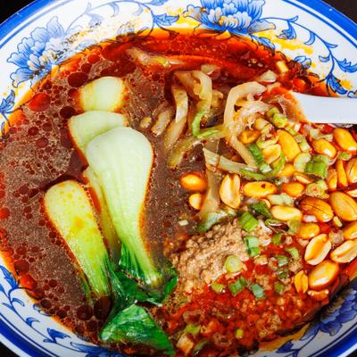Spicy noodle soup with bok choy, peanuts, minced meat, and chili oil.