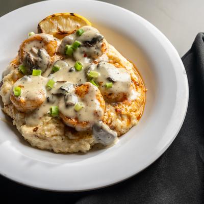 Shrimp and grits topped with creamy sauce and scallions.