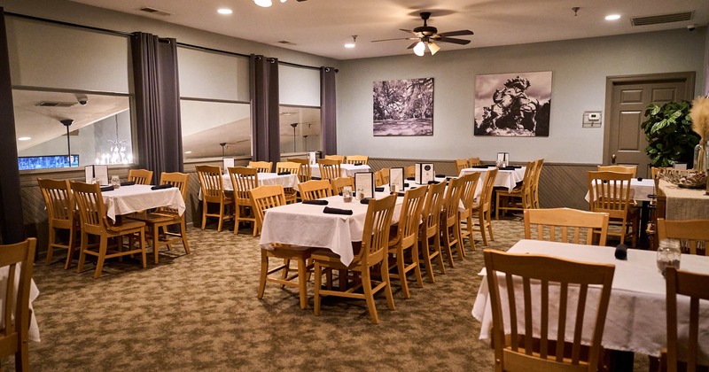 Interior, tables and chairs ready for guests, windows with curtains, carpet flooring
