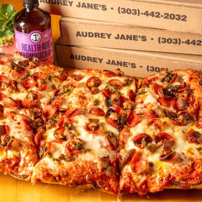 Thick, rectangular Sicilian pizza with pepperoni, sausage, and pizza boxes.
