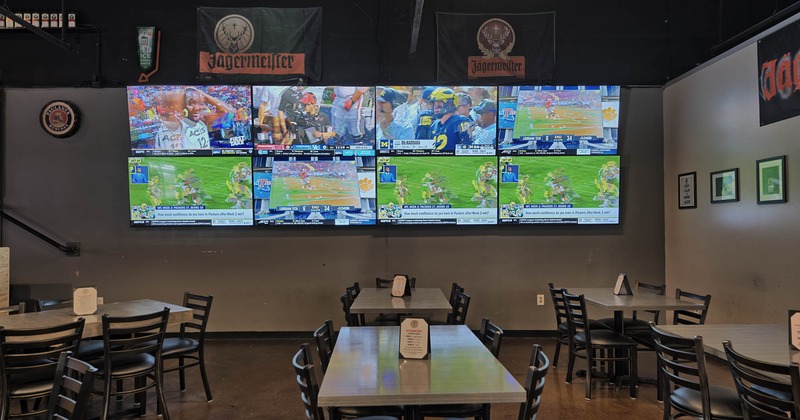 Interior, tables and seats in front of a wall with eight TVs