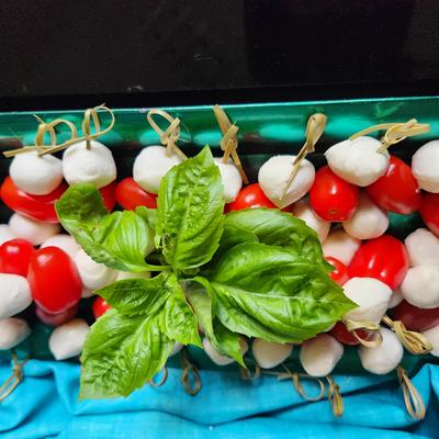 Caprese appetizer skewers with mozzarella, cherry tomatoes, and fresh basil leaves.