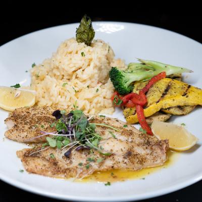 Alaskan Halibut served with lemon wedges, rice risotto, and grilled vegetables.