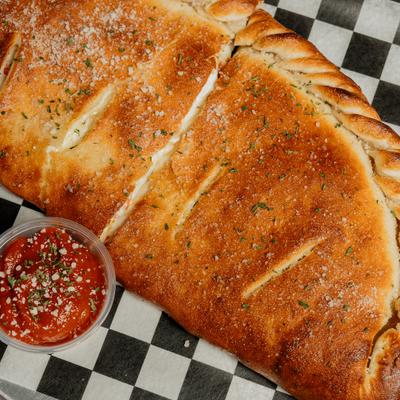 Golden calzone served beside marinara dipping sauce.