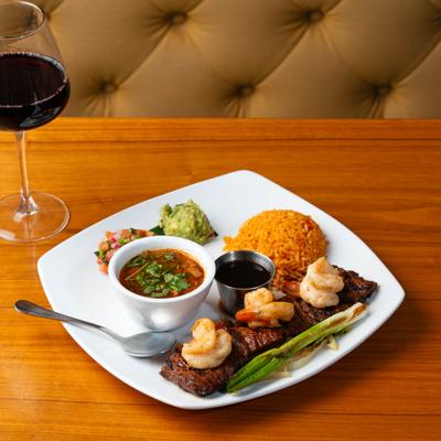 Carne Asada with shrimps, served with glass of red vine.